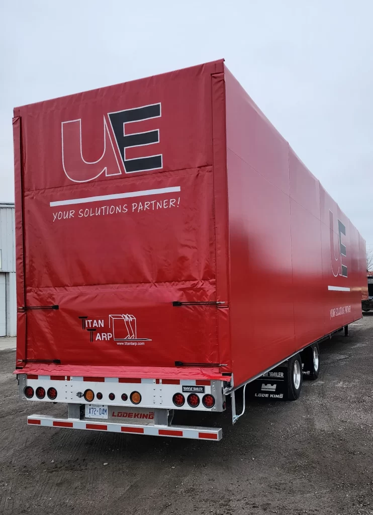 A transport truck trailer with a red tarp with the Titan Tarp branding